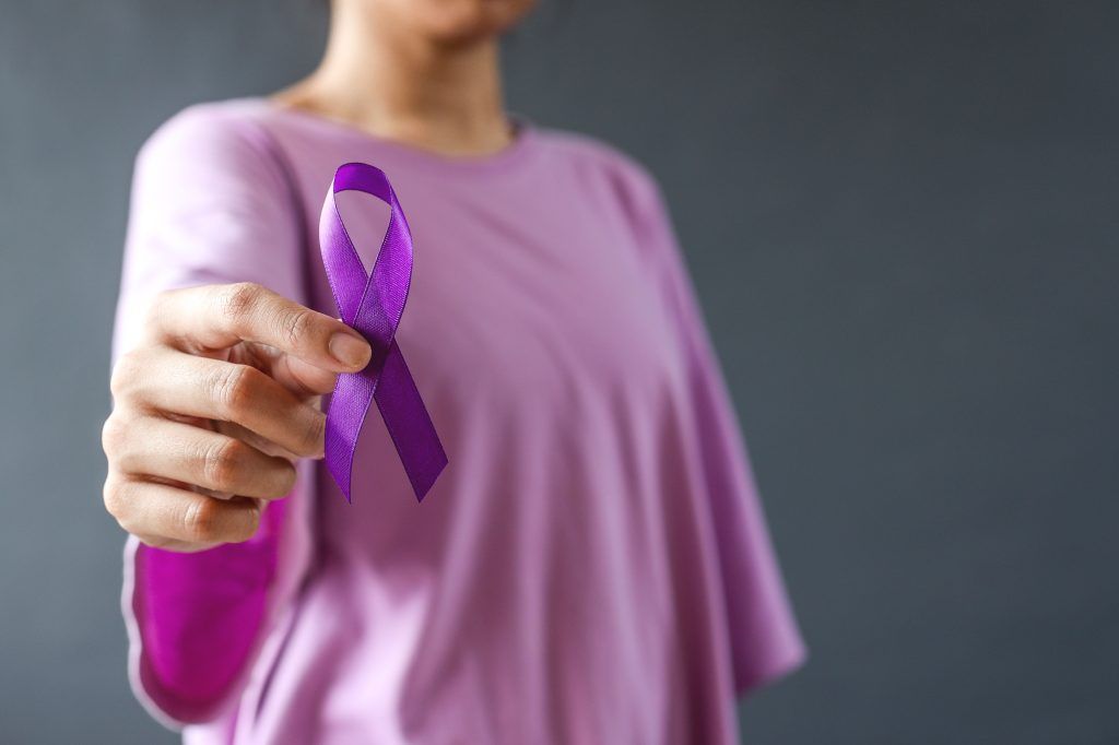 Woman holding purple ribbon on grey background