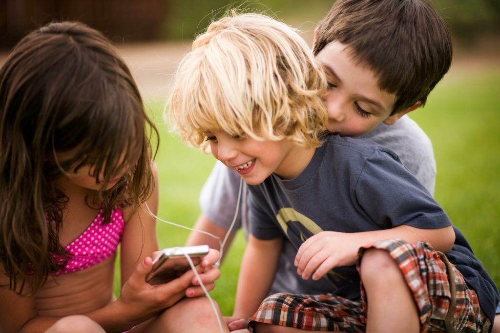 Children listening to earphones outdoors